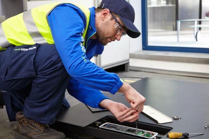 Trabajador haciendo mantenimiento a una báscula
